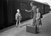 803547 Afbeelding van een vader met zijn twee kinderen op het perron van een N.S.-station.